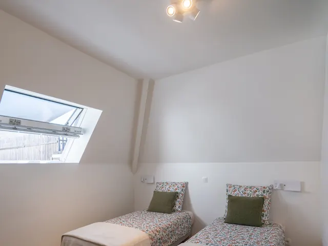 Chambre sous combles avec deux lits simples, fenêtre de toit ouverte, liseuses murales et armoire vert olive, Camuche de Bettignies à Tournai