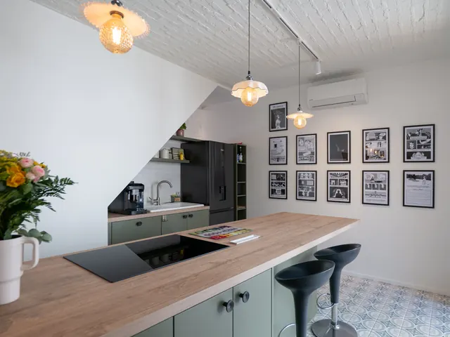 Cuisine vue depuis l'îlot, avec cadres de planches de bande dessinée, suspensions en verre opalin et sol en carreaux à motifs, Camuche de Bettignies à Tournai