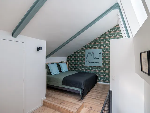 Chambre sous combles avec lit double, papier peint vert et garde-corps en maille noire, Camuche Beyaert à Tournai