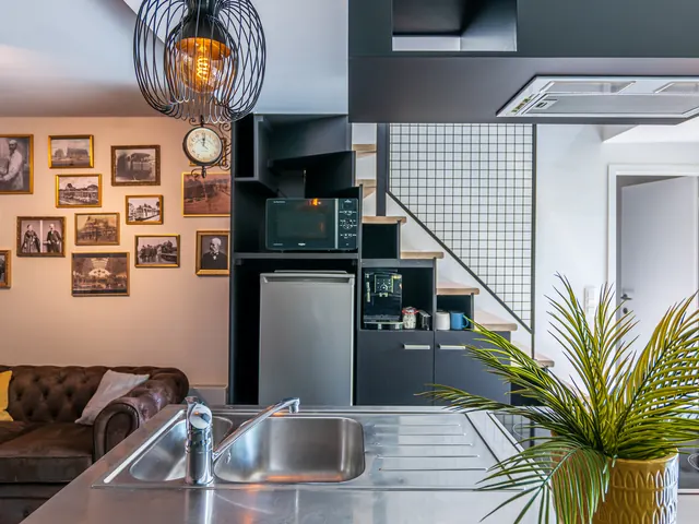 Séjour et cuisine ouverte avec galerie de photos anciennes, escalier et plan de travail en inox, Camuche Beyaert à Tournai