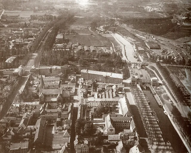 Vue aérienne ancienne d'un quartier de ville avec une église, de grands bâtiments en briques, un canal et un pont, photographie aérienne de René Desclée, archive, Camuche Desclée à Tournai