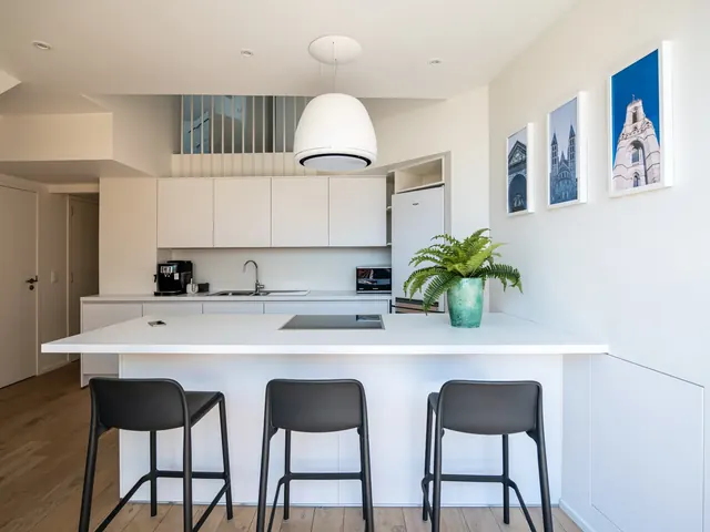 Cuisine blanche avec îlot, hotte suspendue et tabourets noirs, duplex Camuche Desclée à Tournai