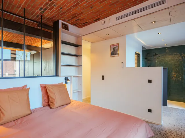 Chambre sous voûte de briques, linge de lit rose corail, verrière d'atelier et douche ouverte derrière une demi-cloison, Camuche Dutrieu à Tournai