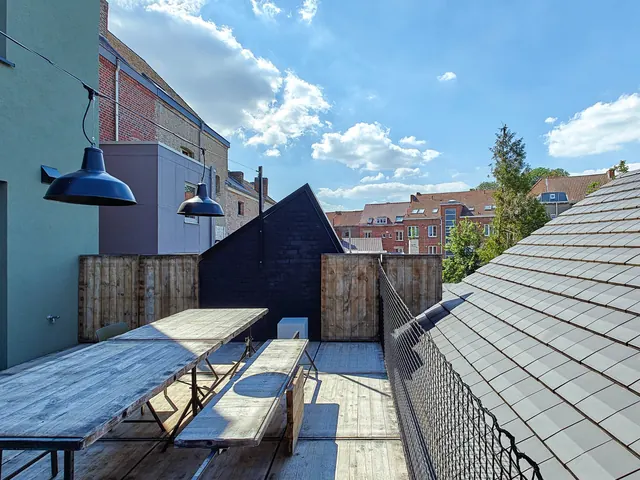 Terrasse arrière avec table en bois, guirlande de suspensions et façade verte, Camuche Dutrieu à Tournai