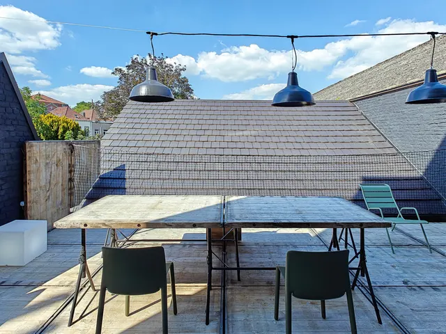 Terrasse arrière avec grande table en bois et suspensions industrielles émaillées, Camuche Dutrieu à Tournai