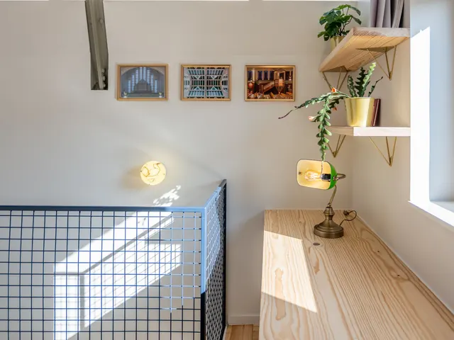 Bureau en bois clair avec lampe de banquier verte, étagères laitonnées et verrières, Camuche Lacoste à Tournai