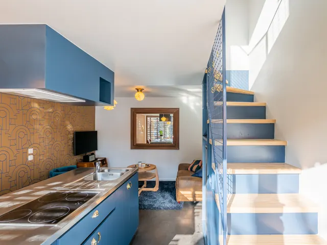 Cuisine bleue aux poignées dorées, papier peint ocre et escalier à garde-corps en maille, Camuche Lacoste à Tournai