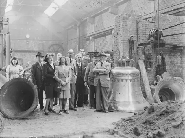 Groupe de visiteurs posant dans l'atelier de la fonderie, entre de grandes cloches de bronze, photographie ancienne, Camuche Michiels à Tournai