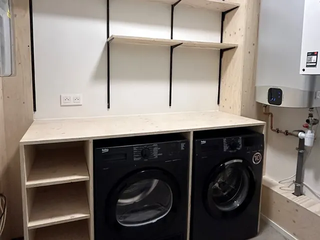 Buanderie équipée d'un lave-linge et d'un sèche-linge noirs, d'étagères et d'un plan de travail en pin, Camuche Michiels à Tournai