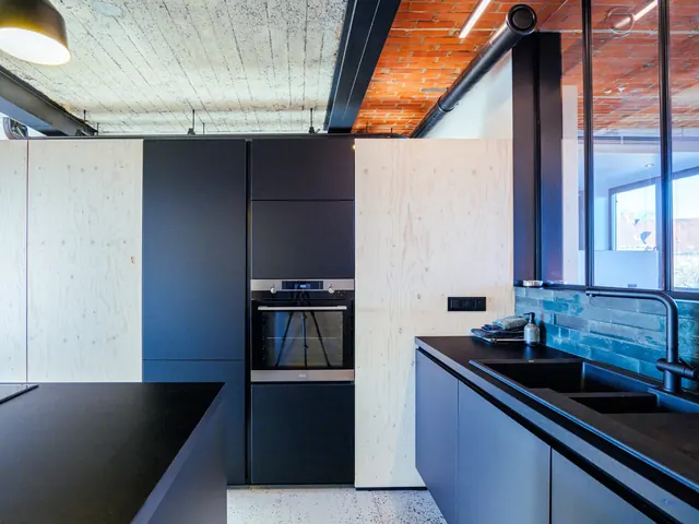 Cuisine noire avec four encastré, caissons en pin et crédence en carreaux bleu-vert, Camuche Michiels à Tournai
