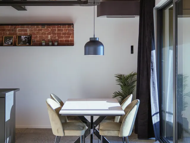 Salle à manger avec table en pin, chaises en velours et suspension noire sous une voûte de briques, Camuche Michiels à Tournai