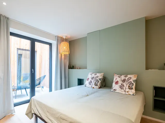 Chambre aux murs verts avec porte-fenêtre ouvrant sur le patio, Camuche Peterinck à Tournai