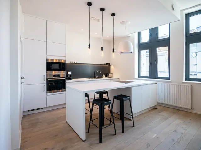 Cuisine équipée avec îlot central et tabourets noirs, Camuche Peterinck à Tournai
